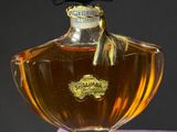 an image of a bottle of perfume sitting on top of a purple box