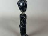 a black figurine of a woman with a hat on her head