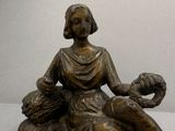 une statue représentant une femme assise sur un rocher avec un chien