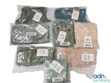 de nombreux t-shirts de différentes couleurs, rangés dans des sacs posés sur une surface blanche