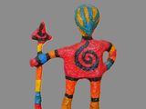 brightly colored figurine of a man holding a staff and a bird