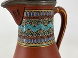 a brown pitcher with a blue and green design on it