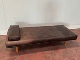 un futon en cuir marron sur lequel est posé un oreiller