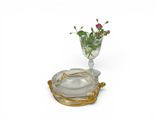 a glass vase with a flower in it on a plate