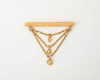 une broche plaquée or composée de trois chaînes et d'une boule