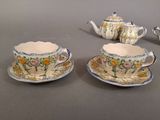 three cups and saucers on a table with a teapot