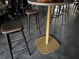 tables and stools in a restaurant with a vase of flowers on the table
