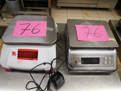 deux balances électroniques posées sur le comptoir, sur lesquelles sont posés des billets roses