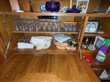 une armoire en bois dotée d'une porte vitrée et d'une étagère sur laquelle sont posés des verres à vin
