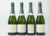 quatre bouteilles de champagne sont alignées sur une surface blanche