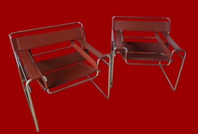 une paire de fauteuils de salon en chrome et en cuir sur fond rouge