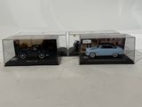 a pair of diecast cars in display cases on a white surface