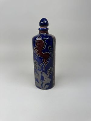 a blue and white vase with a bird on it on a white surface