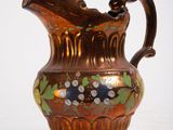a brown pitcher with a floral design on it