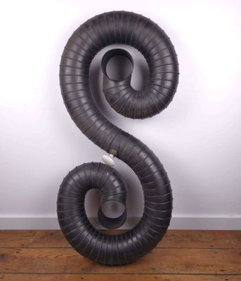 une image représentant un objet noir en forme de spirale posé sur un plancher en bois