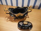a black and gold bowl with a lid on a wooden table