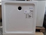 un réfrigérateur blanc posé sur une palette, à côté d'une pile de cartons
