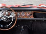 dashboard of a red sports car with a wooden steering wheel and dashboard gauges