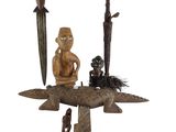 a statue of a man sitting on top of a boat next to other items