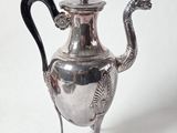 une théière en argent avec une anse en forme de dragon, posée sur un socle