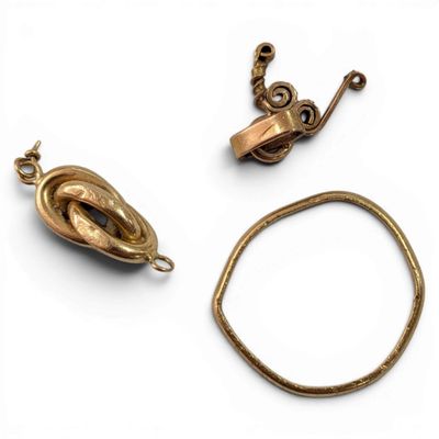 two pieces of gold jewelry on a white surface