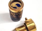 a gold and blue vase with a blue lid next to a gold and blue cup