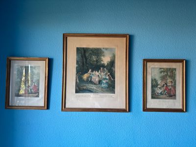 trois tableaux encadrés accrochés au mur d'une chambre bleue