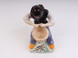 a figurine of a man sitting on a pot