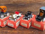 quatre petites voitures posées sur des cartons, sur une table en bois