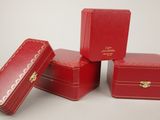 four red leather boxes with gold hardware on them on a white surface