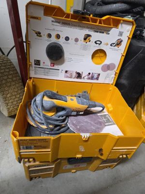 une boîte à outils jaune posée par terre, contenant des outils