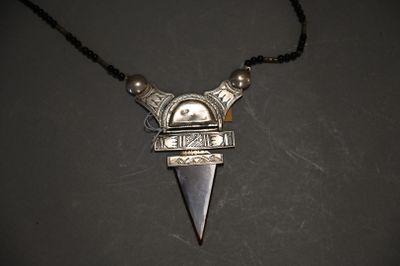 a close up of a necklace with a metal object on a black surface