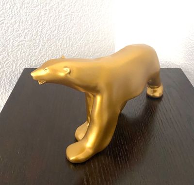 une statue en or représentant un ours polaire, posée sur une table en bois