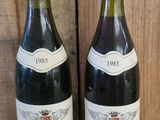 deux bouteilles de vin posées sur une étagère l'une à côté de l'autre