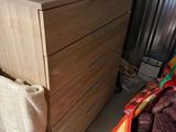 a wooden chest of drawers with a blanket on top of it