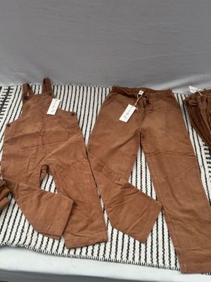 trois paires de pantalons marron posées sur une couverture rayée