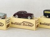 three small toy cars are sitting on top of boxes on a white surface
