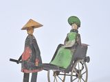 two figurines of a woman and a man in a carriage
