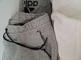 two pairs of sweatpants and a pillow on a bed