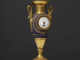 un vase ancien bleu et or, surmonté d'une horloge