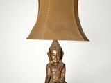 a gold buddha lamp with a brown shade on top of it
