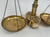 a gold scale with chains hanging from it on a white surface