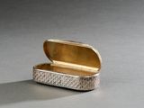 une boîte en argent avec un couvercle en or posée sur une table