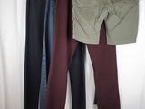 three pairs of pants hanging on a clothes rack in front of a white curtain