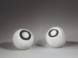 two white balls with black circles on them on a white surface
