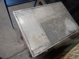 a metal box sitting on the ground next to a blue chair