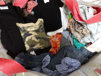 a woman sitting on a bed with a pile of clothes