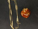 an image of a necklace and an apple on a black surface