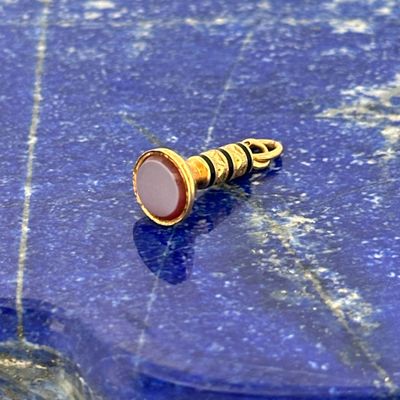 a gold and pink stone bead sitting on a blue surface