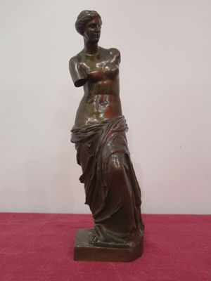 bronze statue of a woman holding a vase on a pink surface